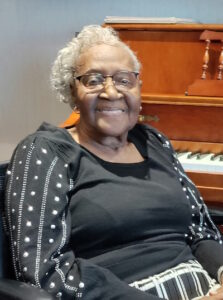 Mary Robinson smiling in front of a piano