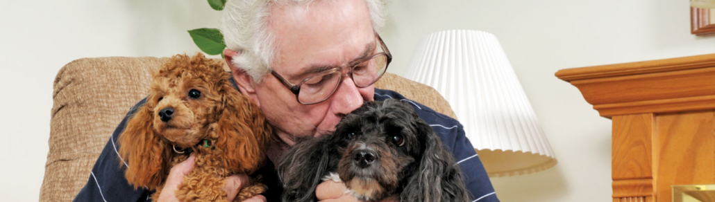 man holding and kissing pet dogs