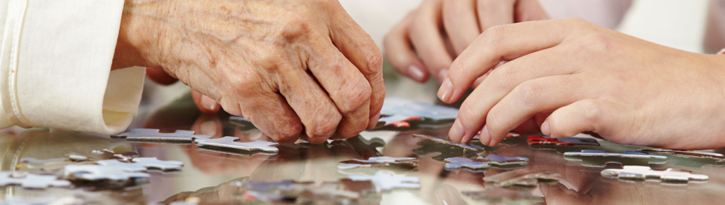 two pairs of hands assembling a jigsaw puzzle