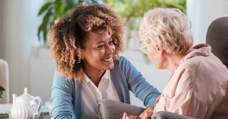 woman smiling at another older woman over tea