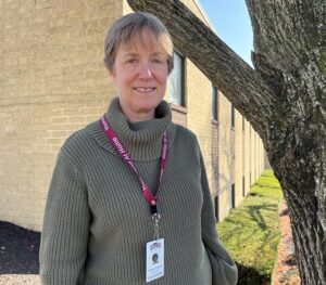Volunteer Susan Stillman smiling outside by a tree