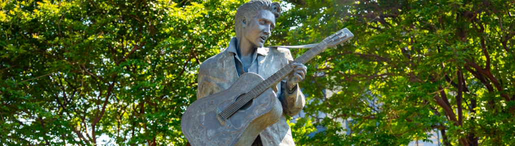 banner featuring a statue of elvis in front of trees